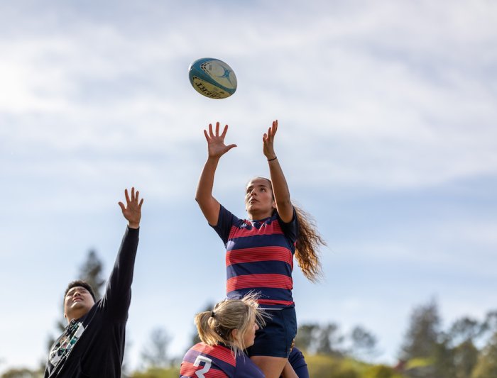 A women's rugby player reaching for the ball
