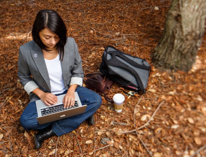 A student writes in the redwood grove.