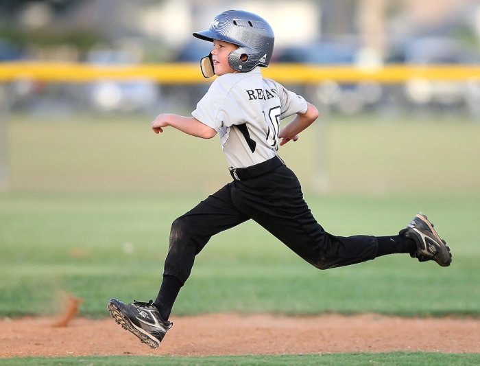 A boy running around a baseball diamond