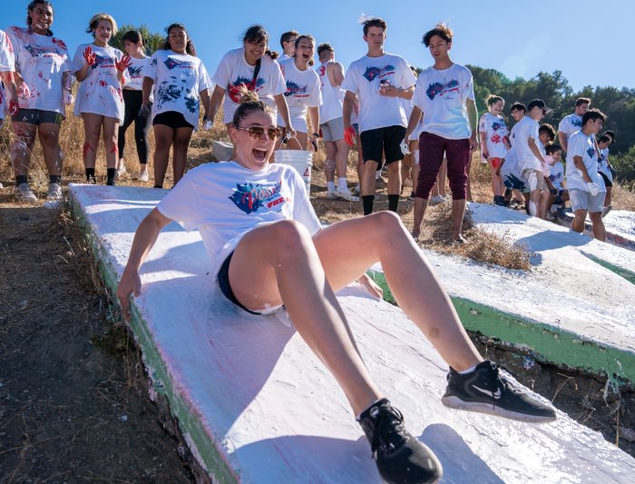 A student sliding down a letter at paint the smc