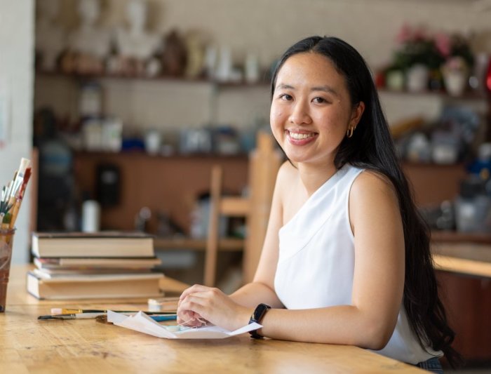 Gabrielle Ly at desk with paint brushes