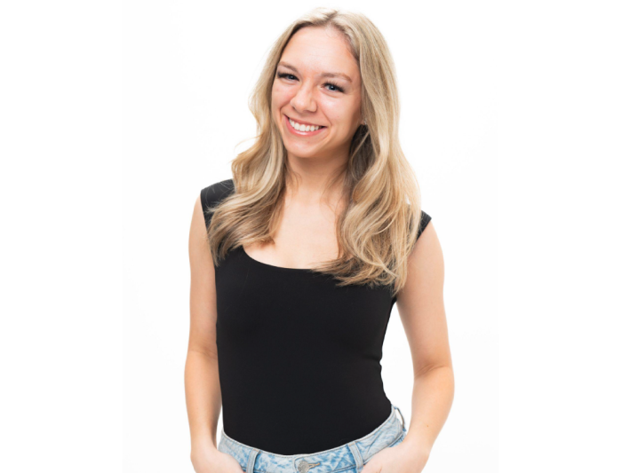 Blonde woman in black shirt in front of a white background.