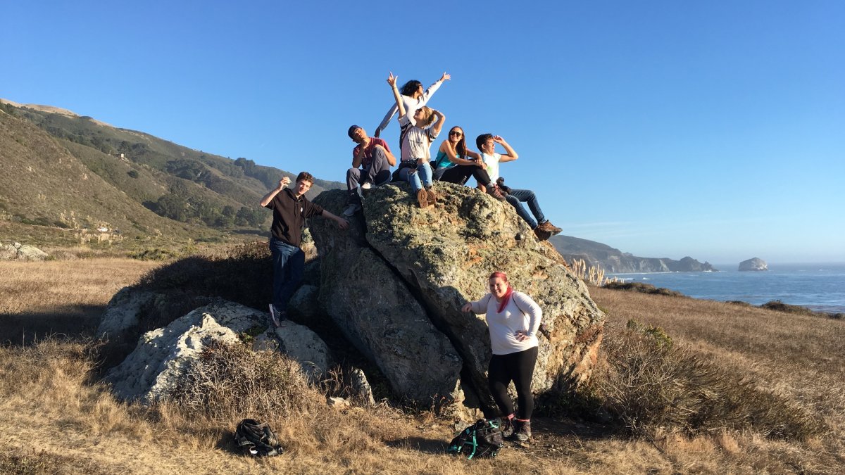 EES students on fieldtrip posing on a coastal rock above the ocean