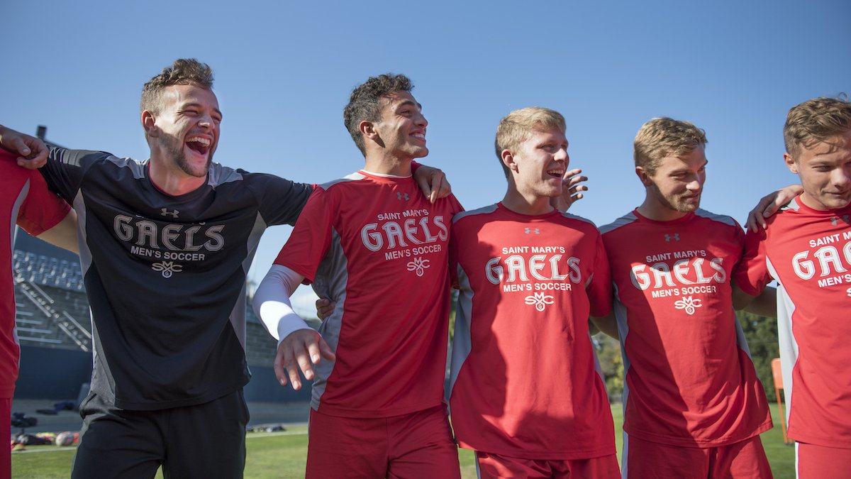 Men's soccer players smile in a huddle