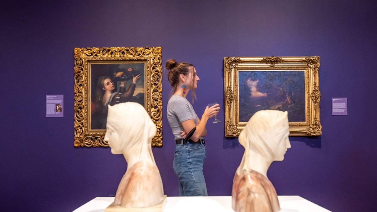 A student standing between two busts at the museum of art