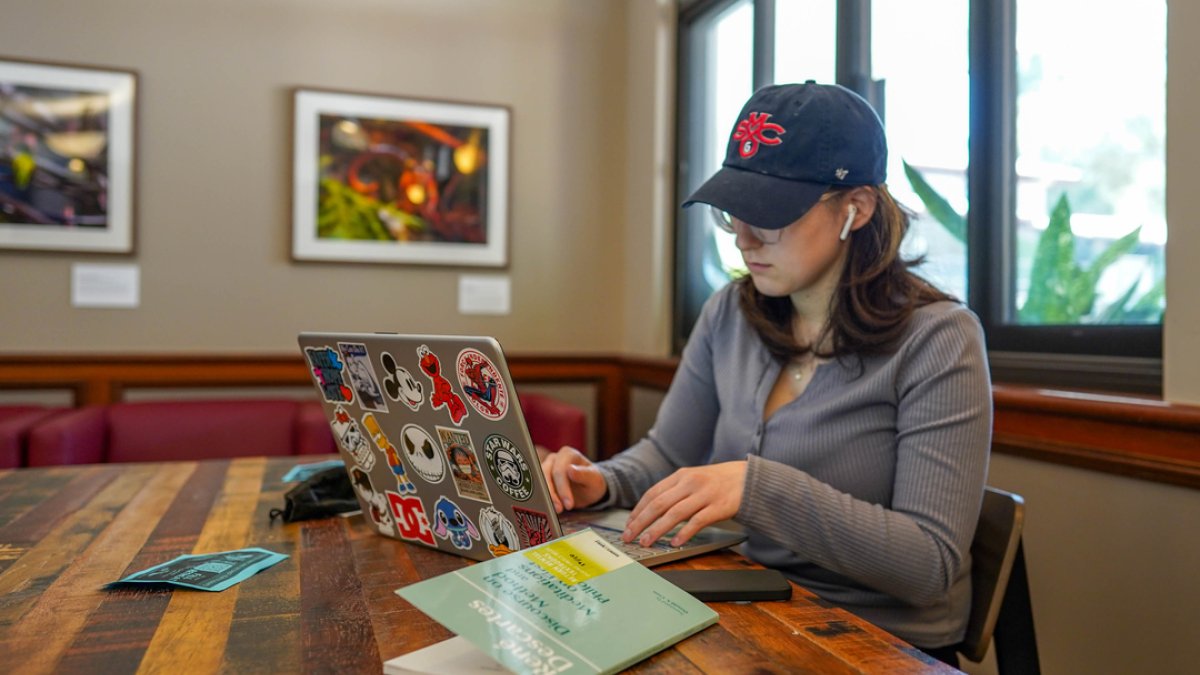 SMC STUDENT WORKING ON LAPTOP IN CAFE