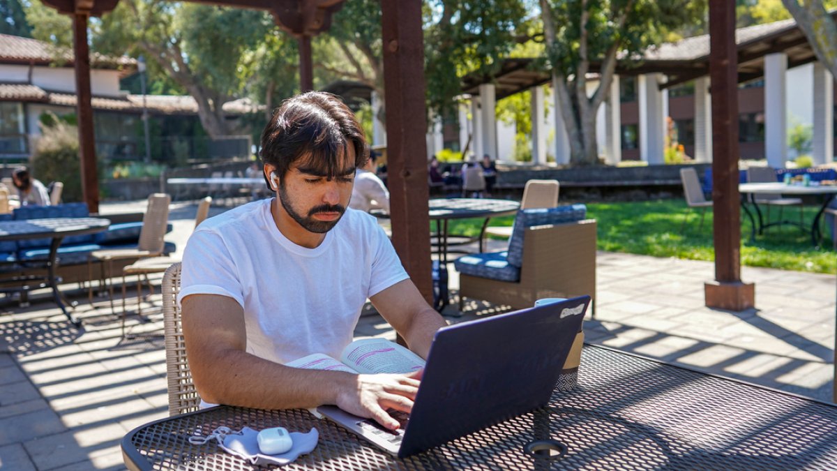 MALE SMC STUDENT WORKING ON COMPUTER OUTSIDE ON CAMPUS