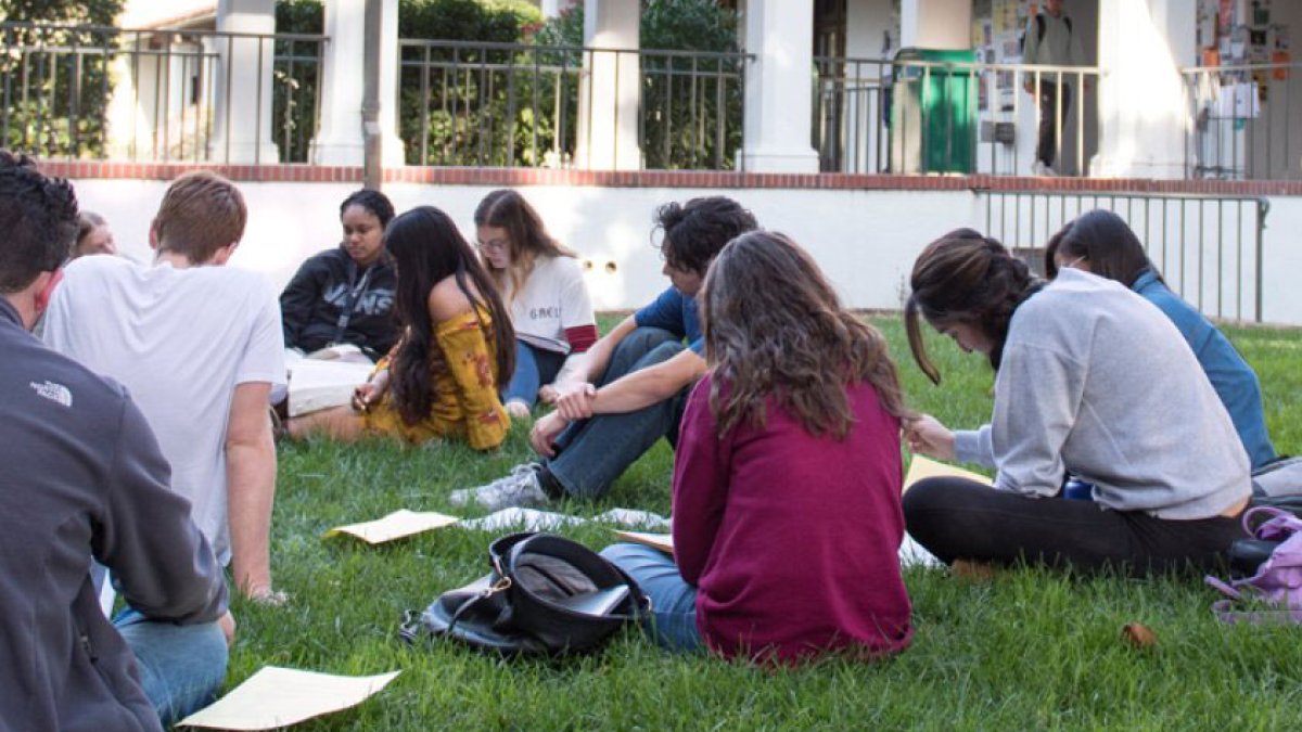 students sitting in grass in circle