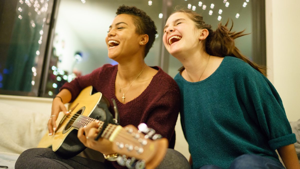 Students smiling and playing guitar