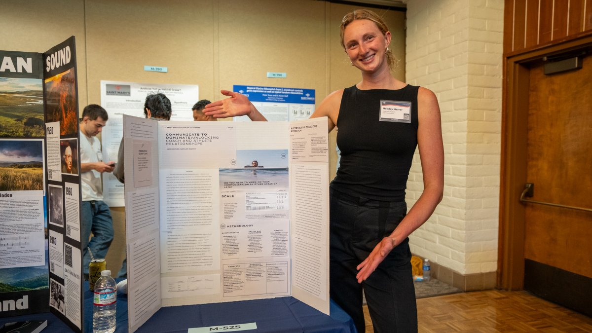 Photo of Hawley Harrer at the Student Research Conference displaying research poster.
