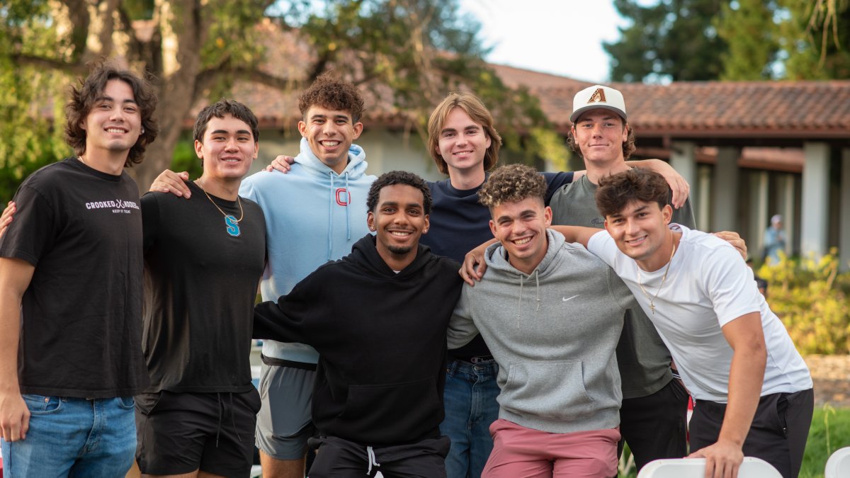 Eight male presenting students stand together